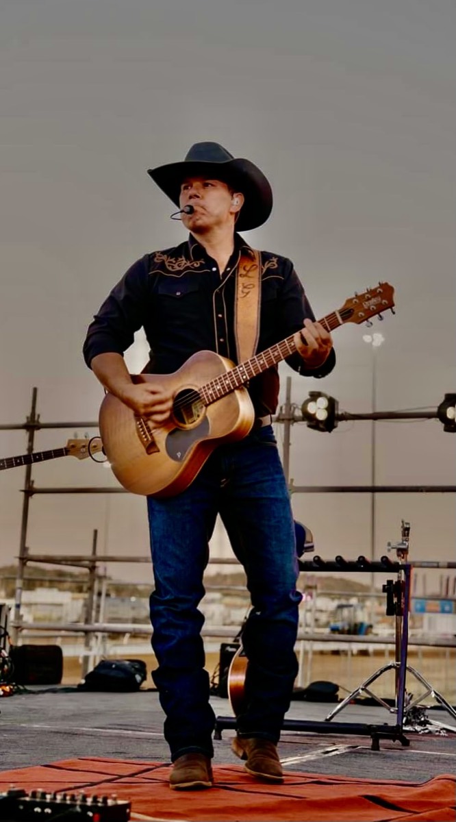 Luke Geiger playing on an outdoor stage at dusk