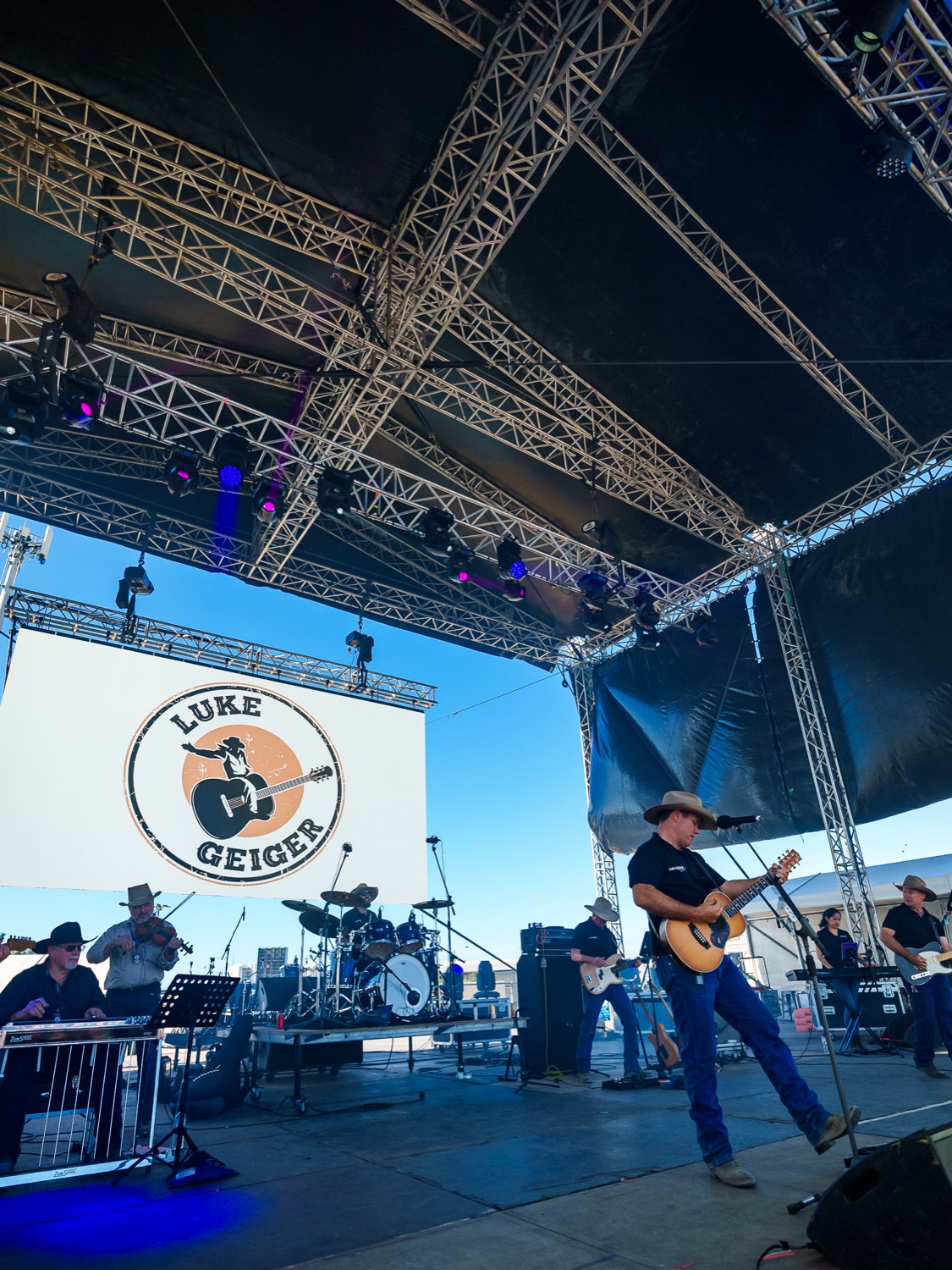 Luke Geiger and band on a festival main stage under lighting truss